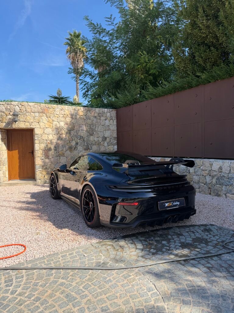 Porsche 911 après detailing, vue 3/4 arrière devant une villa