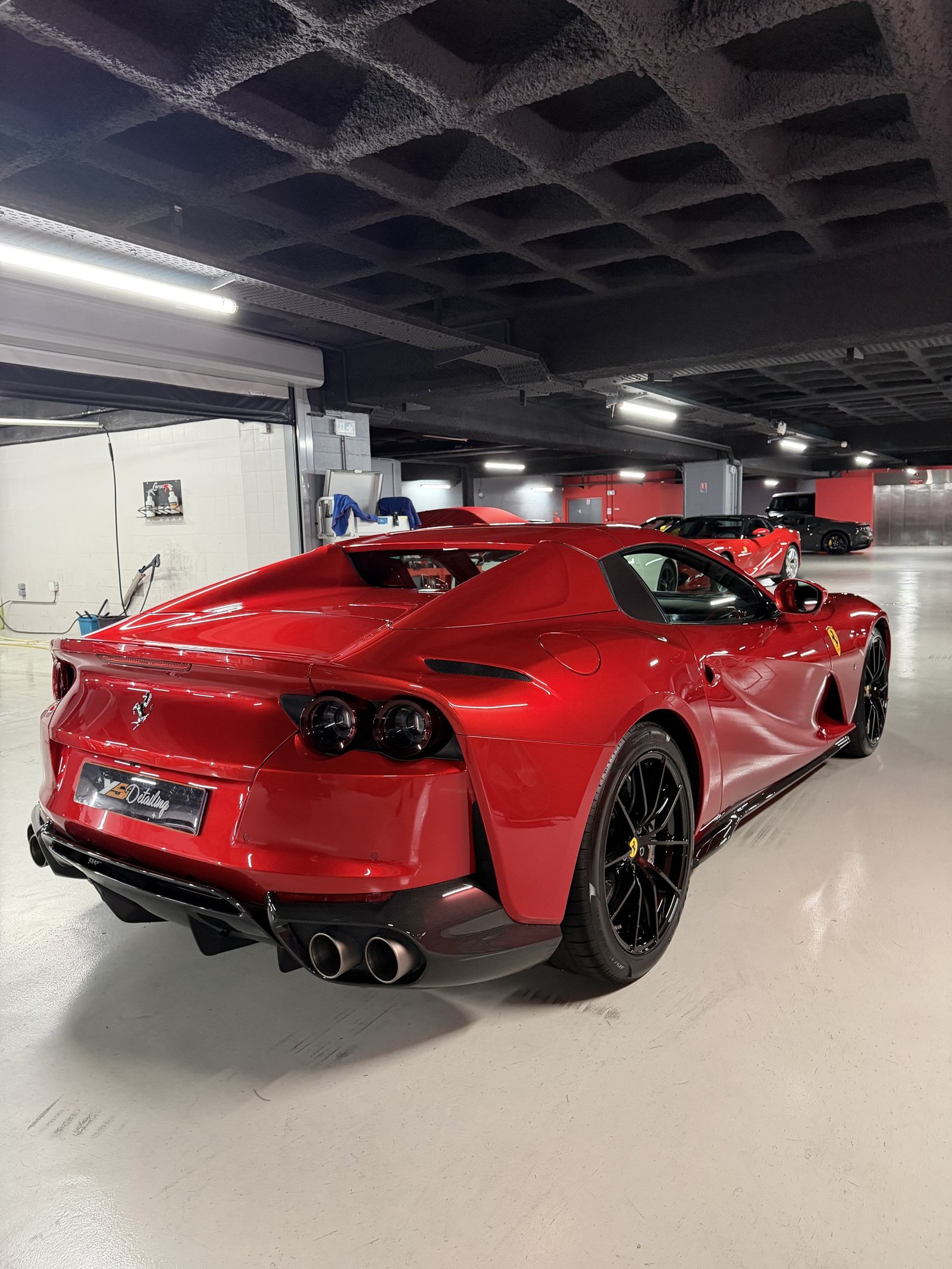 Ferrari 812 rouge vue de trois-quarts arrière, garée dans un parking souterrain